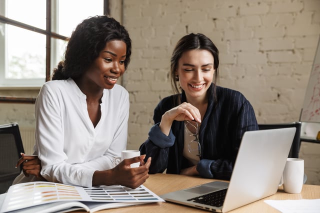 Two colleagues reviewing work together at a desk, representing collaborative partner marketing
